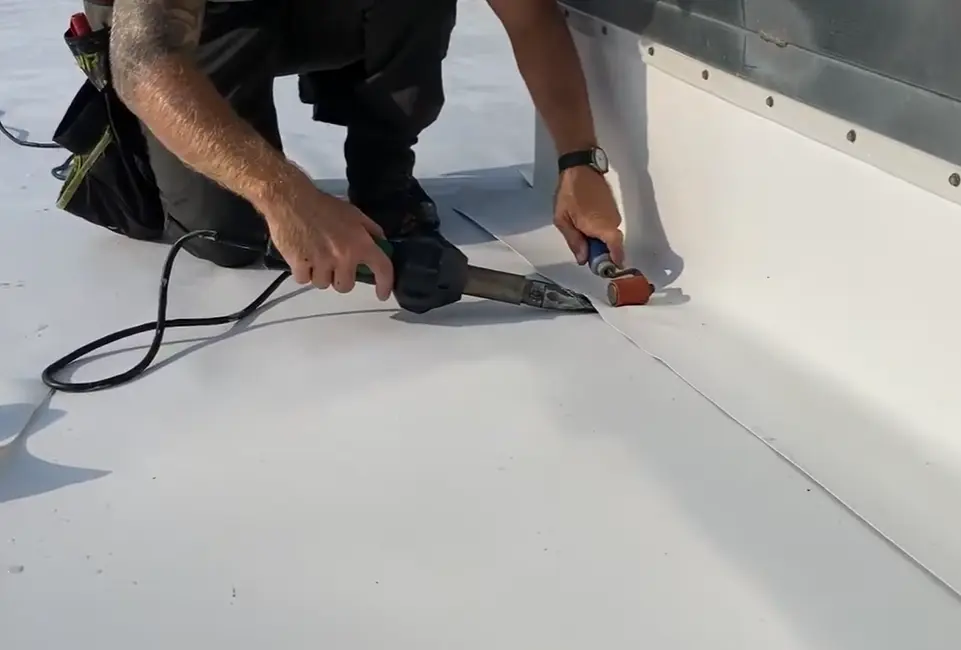 Professional roofer applying liquid sealant to a commercial metal roof in Gainesville