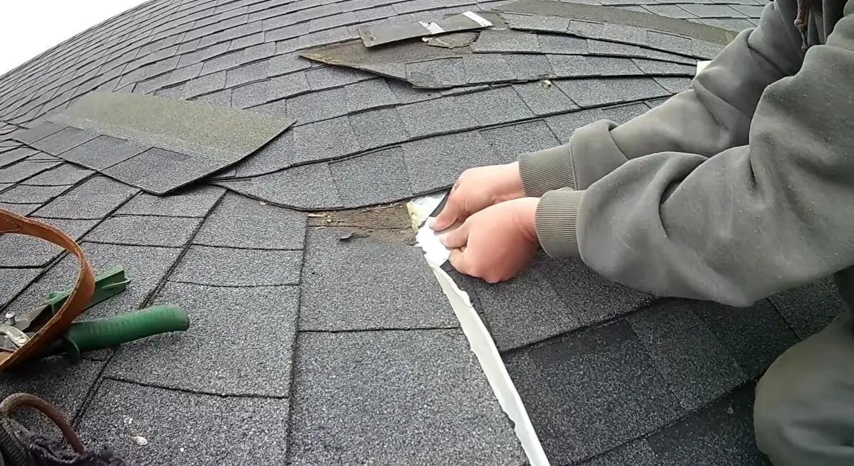 Technician hands performing a shingle roof repair on a Gainesville residential home