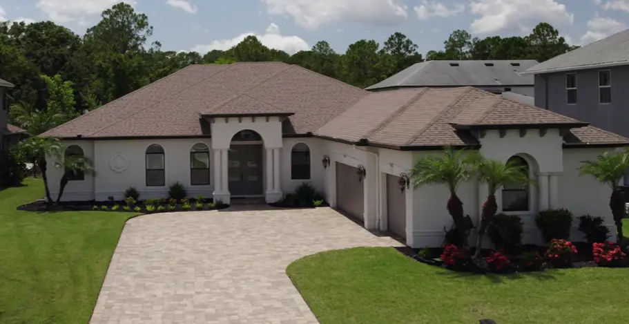 Large white residential home featuring dark architectural asphalt shingles and professional masonry.