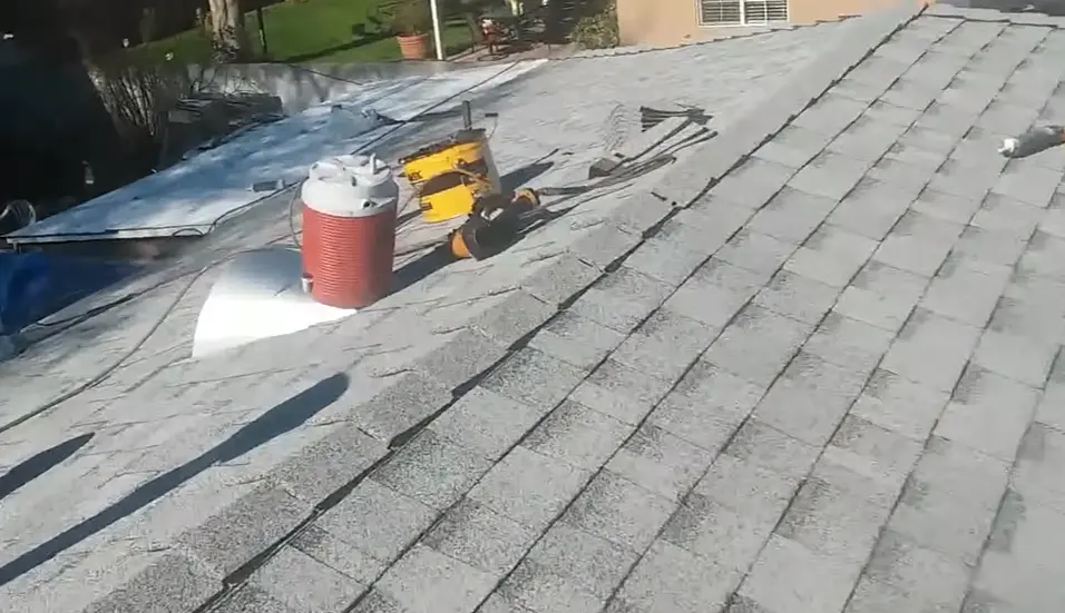 Professional roofing installation showing shingle layering and the ridge line prepared for ridge cap shingles