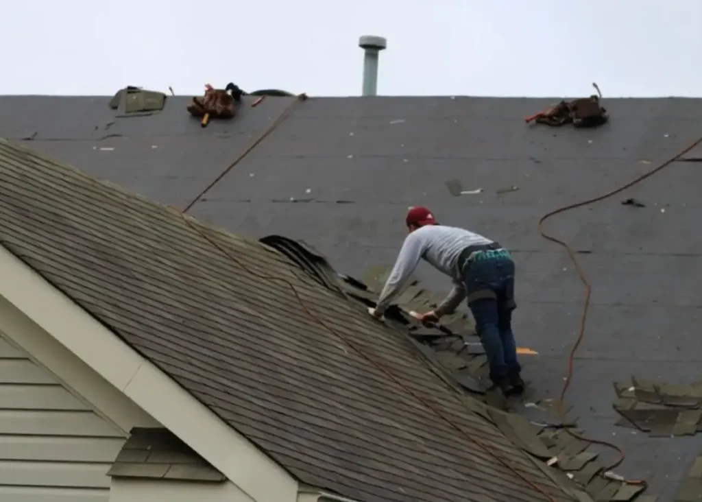 Roofer removing old shingles during an active roof replacement project in Gainesville